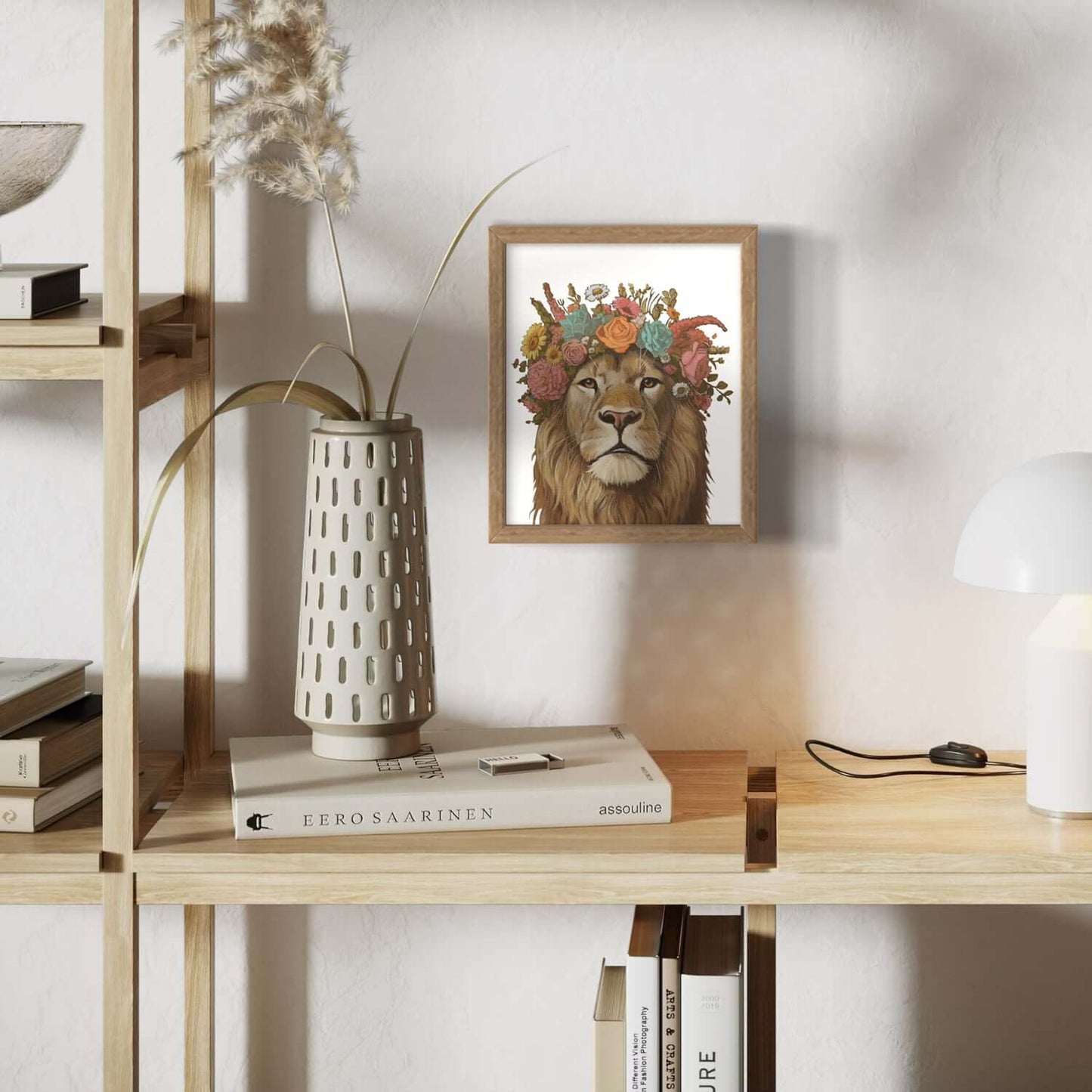 Blumenkind Löwe Print in a wooden frame, decoratively placed on a shelf with a vase and books.