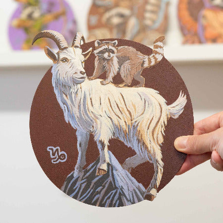 Handgemaltes Retro-Schild mit Steinbock und Waschbär auf einem 20 cm runden MDF-Cut, kreative Wanddekoration.