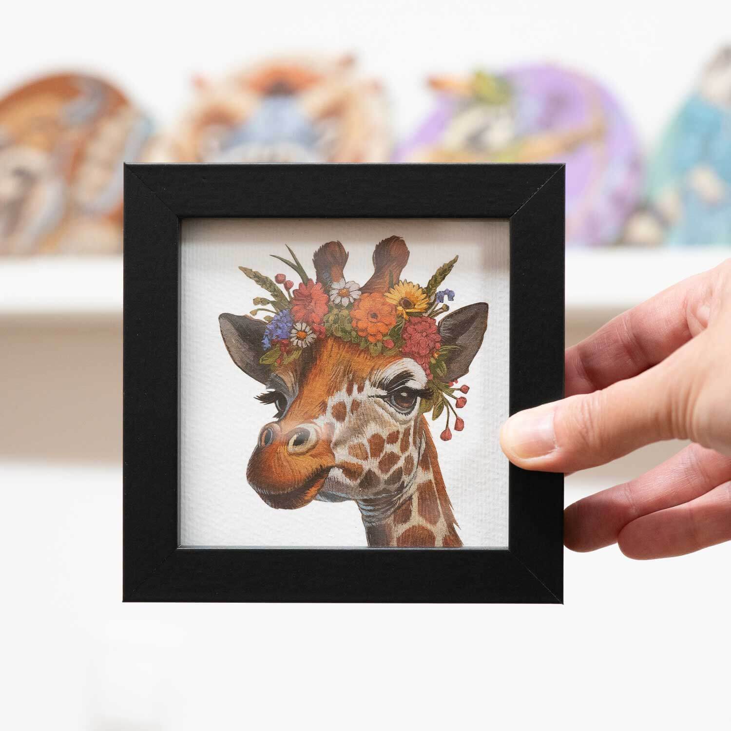 Cute giraffe art print in a black frame, featuring a floral crown. Perfect decor for any space.
