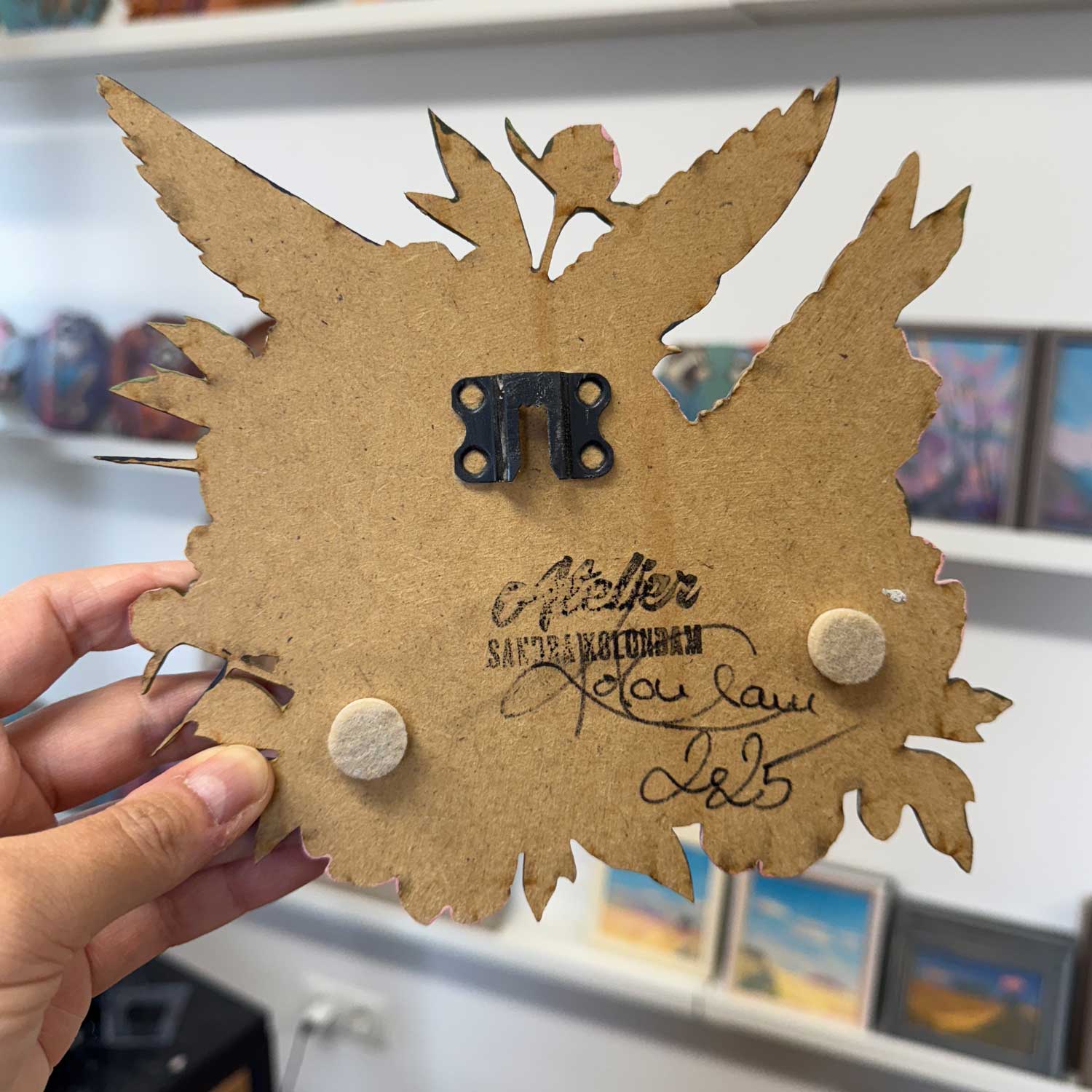 Rückseite eines handgemalten Retro-Schildes mit Aufhängung und Unterschrift, ca. 20x20 cm.